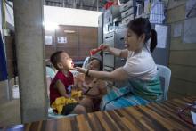 Candy Beau (right), a medic at the Mae Pa clinic, inspects a sick Myanmar child. Candy Beau herself recently contracted Chikungunya and dengue and is dealing with prolonged symptoms. (Luke Duggleby | Frontier)